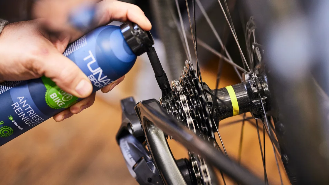 Close-up of a person cleaning a bicycle's rear derailleur with a bike chain cleaner. © TUNAP chemisch-technische Produkte Produktions- und Handelsgesellschaft m.b.H.