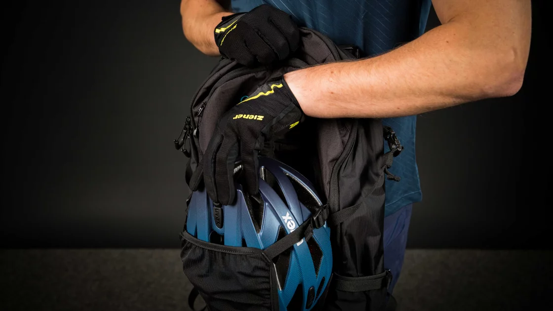 Mann verstauert einen Fahrradhelm in einem Rucksack. © Sport Kessler GmbH