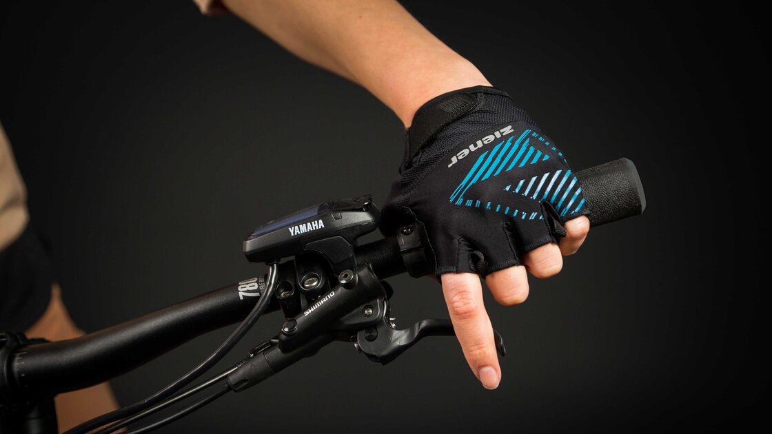 Close-up of a hand wearing a cycling glove gripping the handlebars of an electric bicycle. © Sport Kessler GmbH