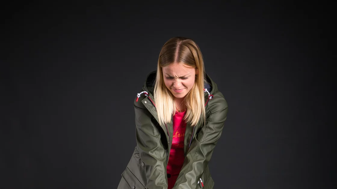 Studioaufnahme: Junge Frau in olivgrüner Jacke und rosa Hose mit Plüschhund. © Sport Kessler GmbH