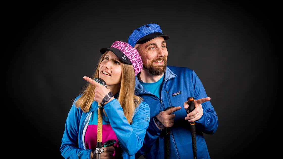 Mann und Frau in blauen Jacken mit Wanderstöcken zeigen in verschiedene Richtungen. © Sport Kessler GmbH