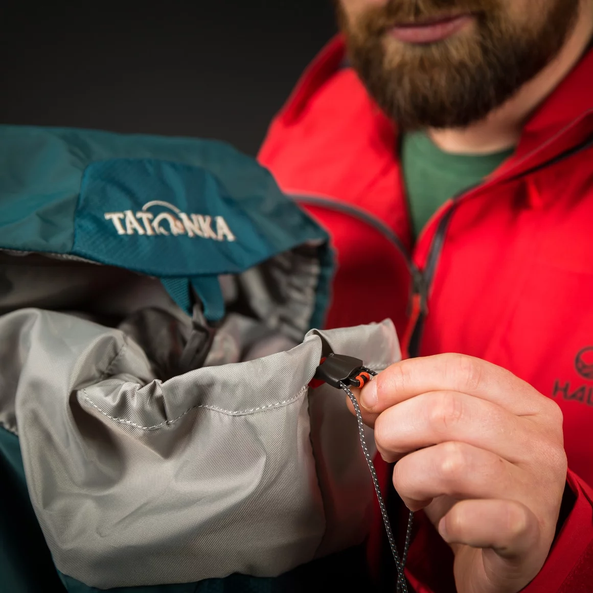 Mann schließt einen türkisfarbenen Tatonka-Rucksack. © Sport Kessler GmbH