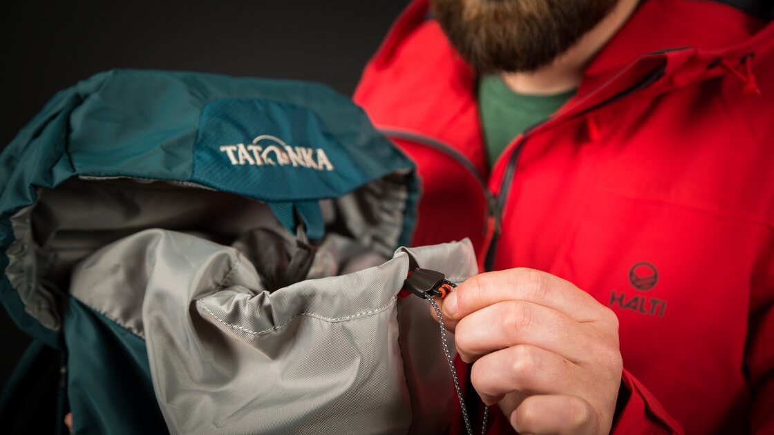 Mann schließt einen türkisfarbenen Tatonka-Rucksack. © Sport Kessler GmbH
