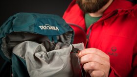 Mann schließt einen türkisfarbenen Tatonka-Rucksack. © Sport Kessler GmbH