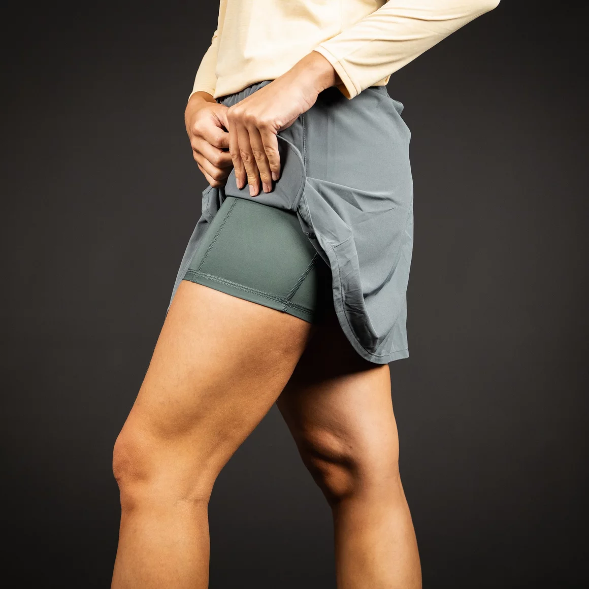 Woman adjusting a gray athletic skirt with built-in shorts. © Sport Kessler GmbH