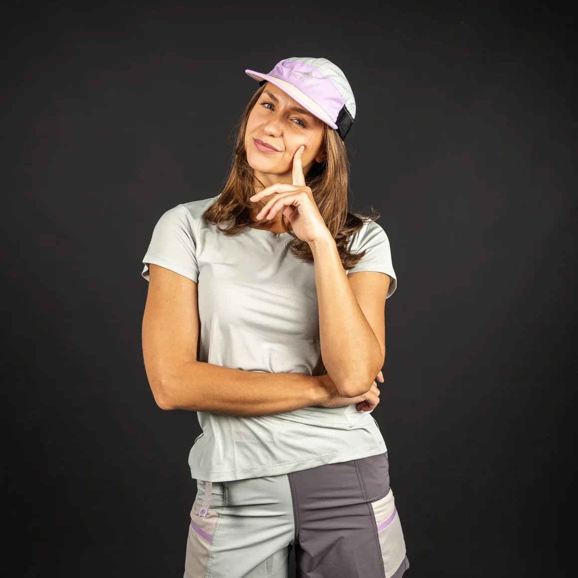 Eine junge Frau mit braunen Haaren und einer lila Baseballmütze vor dunklem Hintergrund. © Sport Kessler GmbH