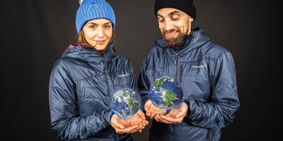 Zwei Personen in blauen Outdoor-Jacken halten leuchtende Hologramm-Erden in ihren Händen. © Sport Kessler GmbH