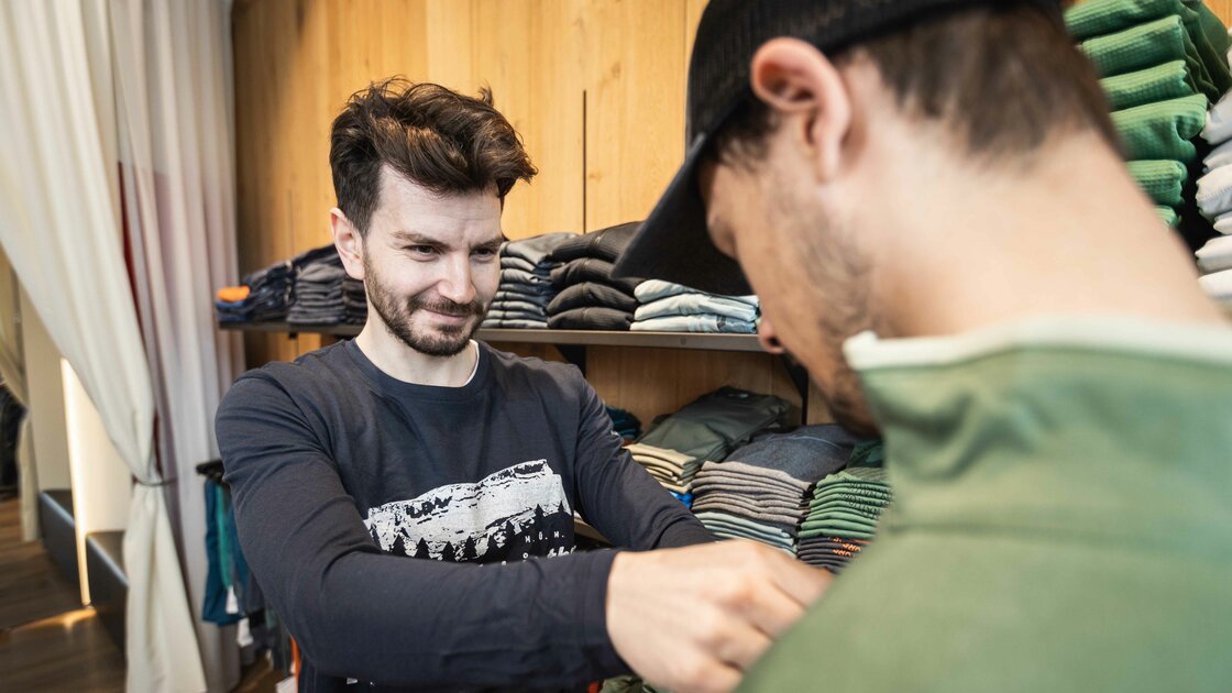 Verkäufer hilft Kunde bei der Auswahl von Kleidung im Geschäft. © Sport Kessler GmbH