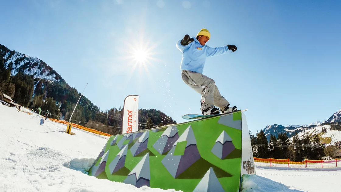 Snowboarder springt über eine Rampe in den Bergen. © Sport Kessler GmbH