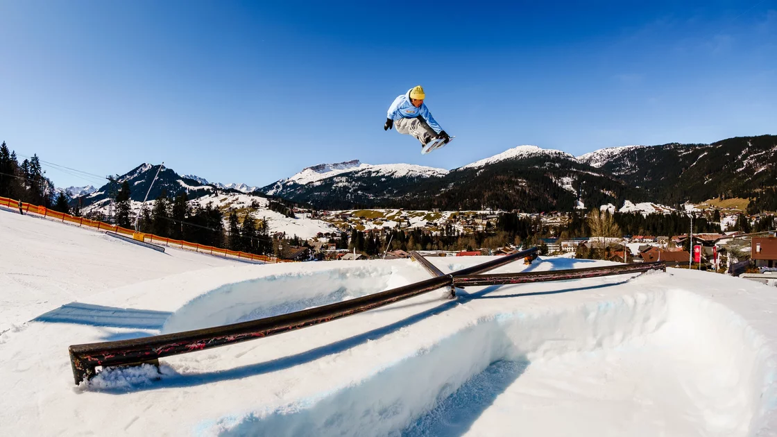 Snowboarder performing a trick over a snow feature in the Alps. © Sport Kessler GmbH