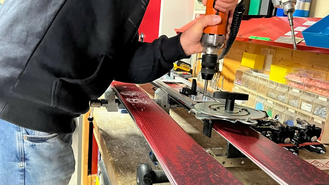 Skiservice: Ein Mann befestigt mit einer Bohrmaschine Bindungen an Skiern. © Sport Kessler GmbH