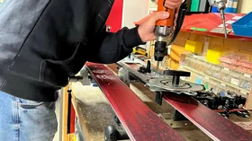 Skiservice: Ein Mann befestigt mit einer Bohrmaschine Bindungen an Skiern. © Sport Kessler GmbH