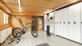Man storing helmet in locker in a ski and bike storage room. © Sport Kessler GmbH