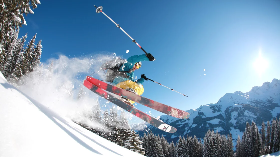Skier performing a jump in snowy mountains. © Sport Kessler GmbH