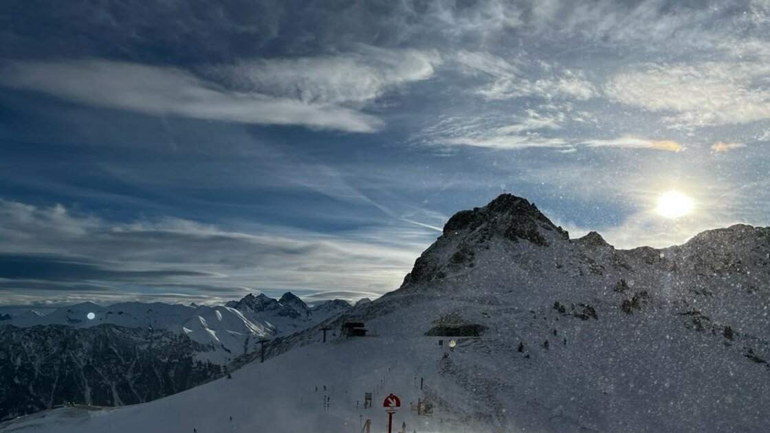 Skifahrer auf verschneiter Piste mit Bergpanorama bei Sonnenuntergang. &copy; Sport Kessler GmbH