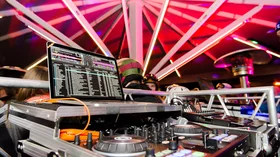 DJ equipment at a party under a pink and purple light structure. © Plattform Kleinwalsertal