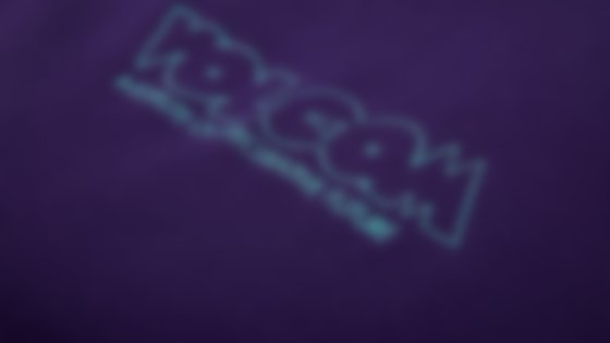 Nahaufnahme eines dunkelvioletten Stoffes mit einer helltürkisen Stickerei des Logos „Volcom Institute of Speculative Future“. © Sport Kessler GmbH